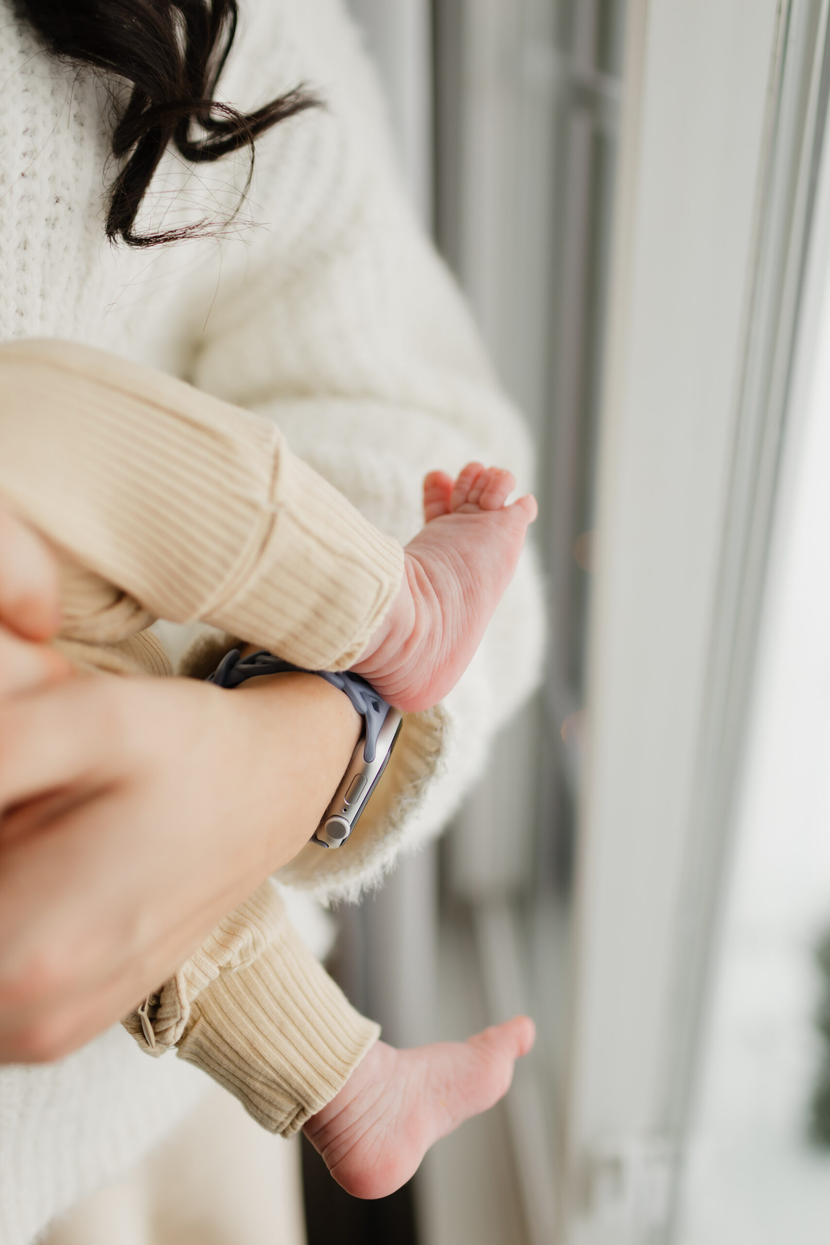 A mom holding her baby in her arms with the baby's feet peaking through.