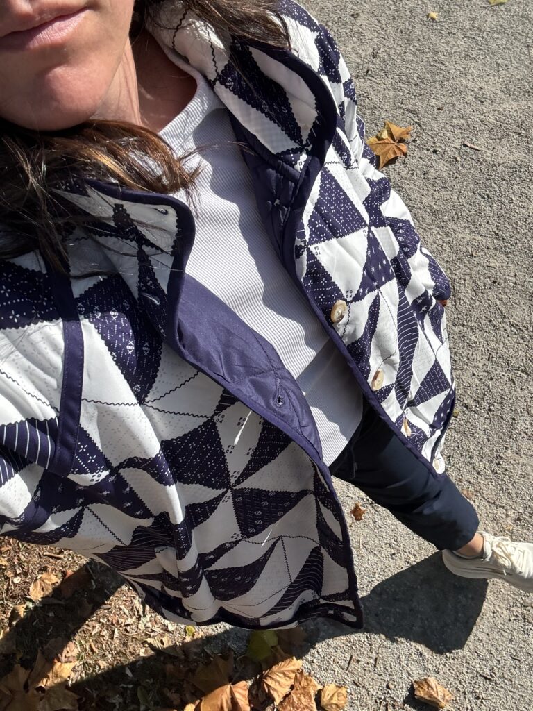 Top down photo of a woman wearing a quilted navy blue puffer jacket, with buttons and quilt patterns.