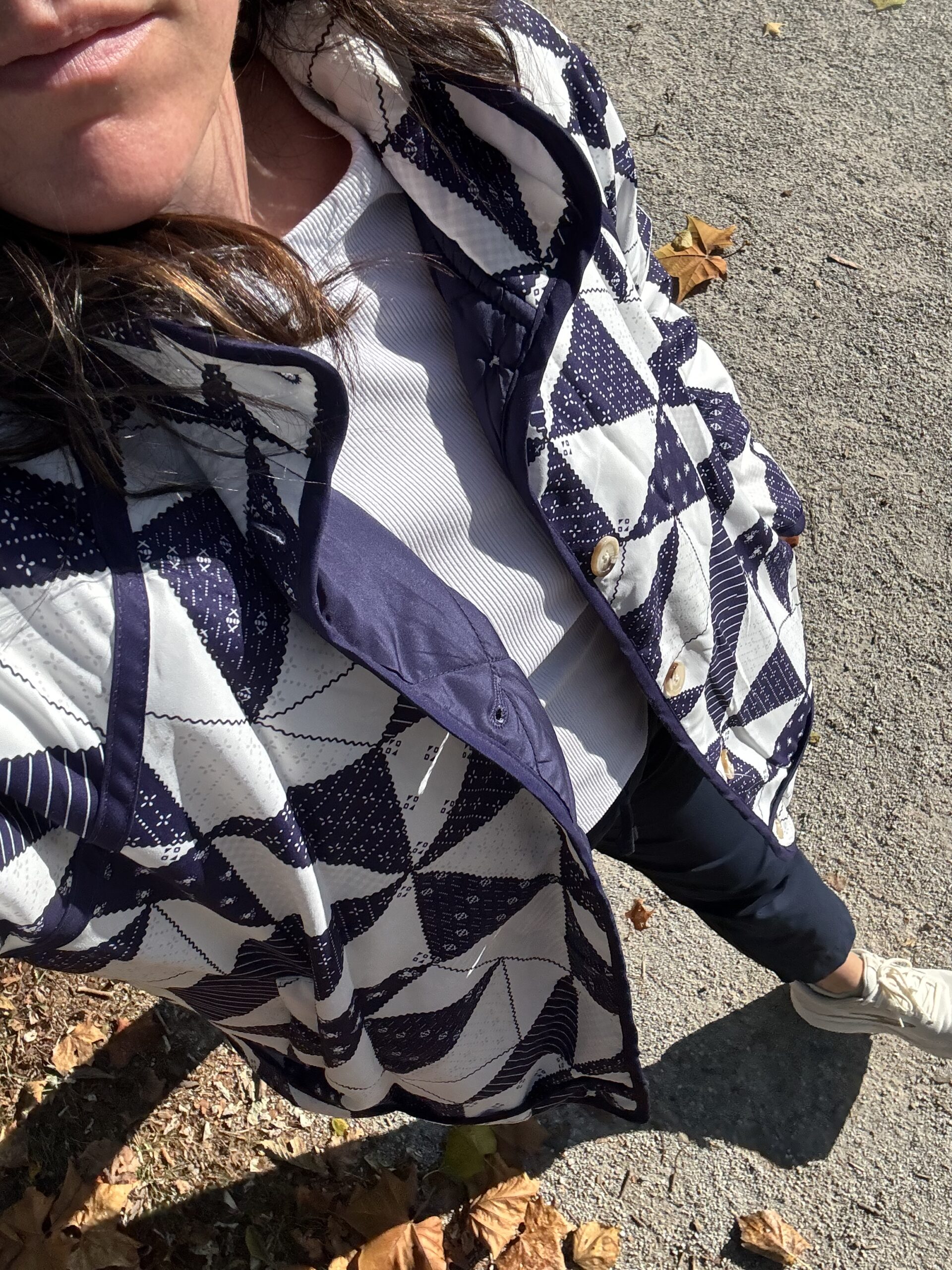 Top down photo of a woman wearing a quilted navy blue puffer jacket, with buttons and quilt patterns.