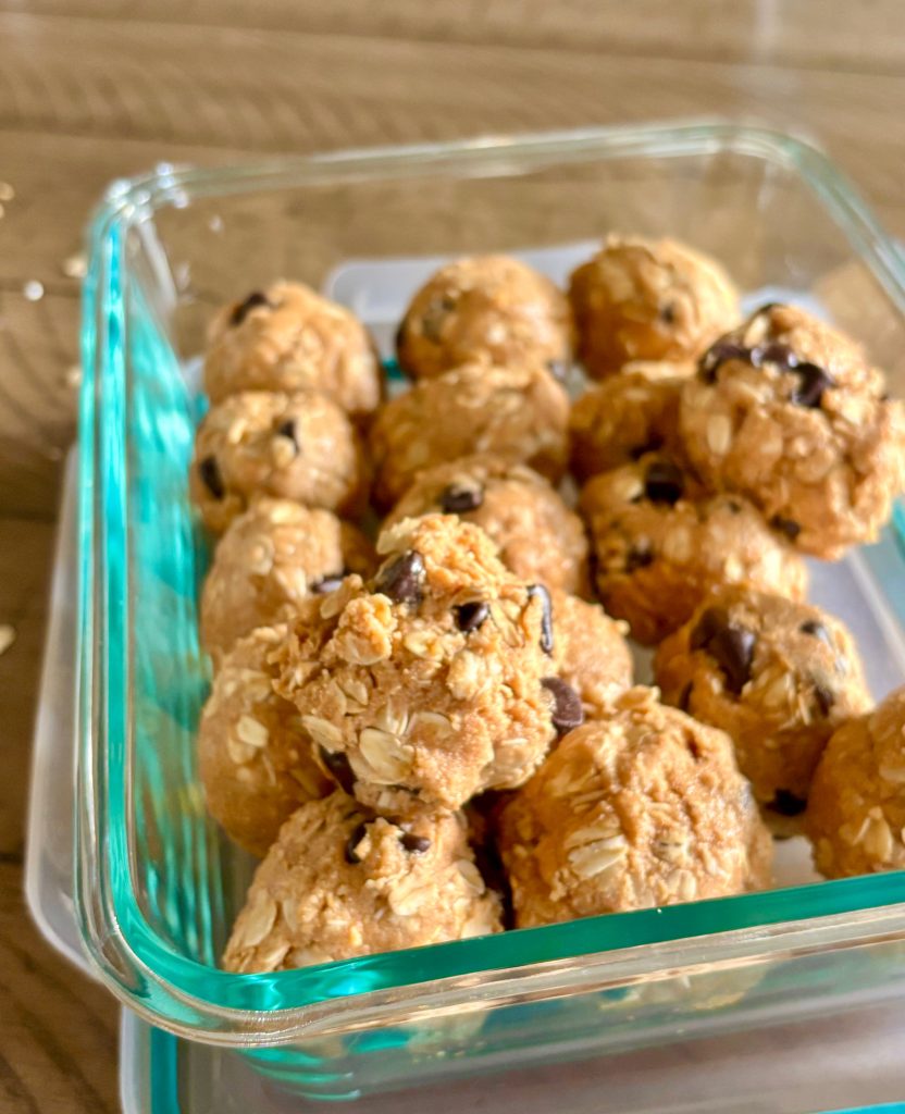 Top down view of protein balls in a glass container with chocolate chips, oats, and peanut butter.