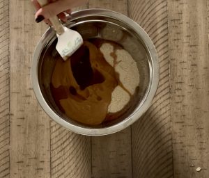 Top-down view of ingredients in a bowl, honey, oats, protein powder, peanut butter.