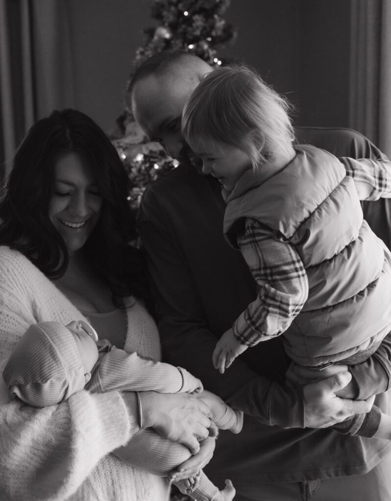 Family looking at baby with a Christmas tree in the background.