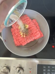 Top-down view of ground beef for shepherd's pie with seasoning on it in a pan.