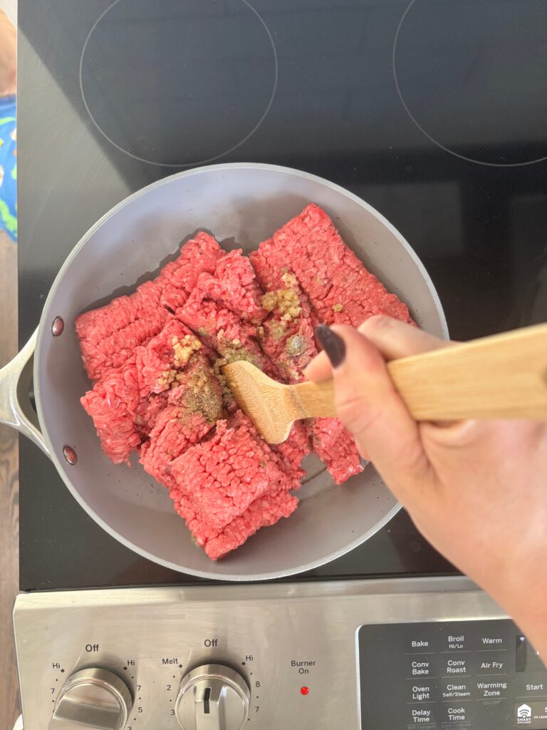 Top down view of ground beef inside a skillet being browned with spices.