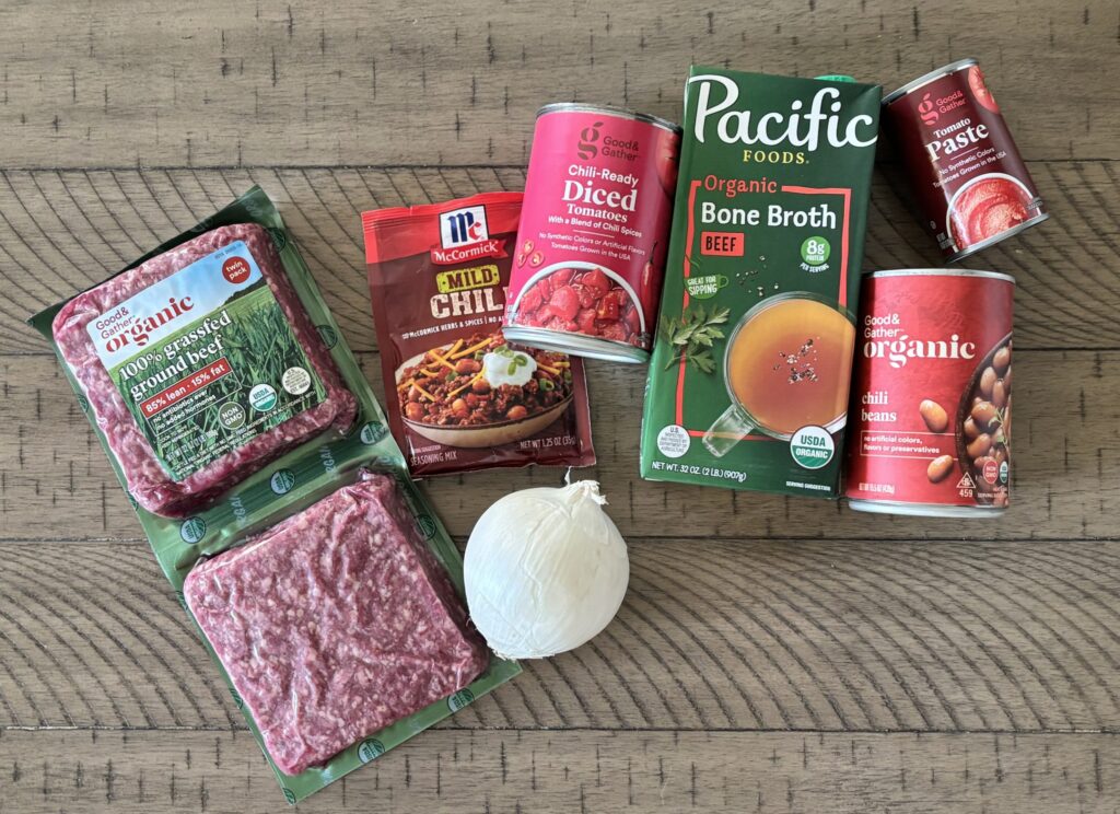 Top-down view of low carb chili ingredients which include ground beef, tomato paste, bone broth, onion and chili beans.